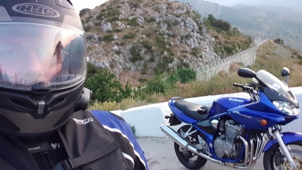 Suzuki Bandit with rider and mountain views.